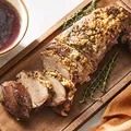 a large piece of meat sitting on top of a cutting board next to a bowl of sauce