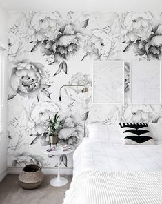 a white bed sitting next to a wall with flowers painted on it's walls