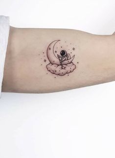 a person's arm with a small tattoo on it, and the moon in the sky