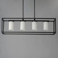 four lights hanging from a metal frame in a room with gray walls and flooring