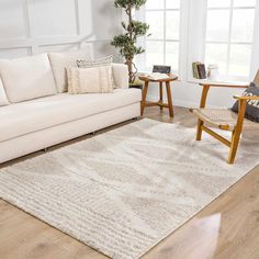 a living room filled with furniture and a rug on top of a hard wood floor