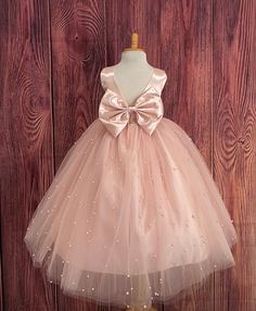 Our enchanting Ankle Length flower girl dresses are sure to turn heads! Bodice is made of Blush satin, waist consists of a matching sowed in sash (NOT DETACHABLE) The back of the dress has an open deep V-Back with a hidden zipper, followed by a detachable bow. The skirt has 4 tulle layers for fullness, the top layer of tulle consists of pearls. The dress has 2 layers of lining with crinoline. This dress is perfect for any occasion!  Dress Is Pictured with a petticoat NOT INCLUDED https://www.etsy.com/listing/1305138635/white-ankle-length-petticoat-wedding?click_key=50d449c187c9e82c565249da914d7ed38b32b9f7%3A1305138635&click_sum=17db9314&ref=shop_home_active_2 Visit our store, more items to come!  https://www.etsy.com/shop/LittledarlnBoutique?ref=profile_header CUSTOM MEASUREMENTS AVAILABLE Princess Style Satin Ball Gown For Pageants, Princess Dress With Satin Bow For Dress-up, Pageant Princess Dress With Satin Bow And Tulle, Pageant Princess Dress With Satin Bow, Pageant Tulle Ball Gown With Satin Bow, Princess Style Satin First Communion Dress, Satin Princess Dress For Dress-up, Bridesmaid Princess Dress With Satin Bow, Satin Bridesmaid Princess Dress With Satin Bow