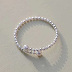 Experience elegance redefined with our "Eternal Embrace" White Freshwater Pearl Bracelet. Two large pearls gracefully frame the open closure, forming a captivating large circle that symbolizes unity and endless beauty. The design's simplicity accentuates the pearls' natural allure, making it a versatile piece suitable for both casual and formal occasions. A classic with a contemporary twist, this bracelet is a timeless addition to any jewelry collection. Pearl size 5-7mm Note: Our jewelry is han Elegant Sterling Silver Pearl Bangle Bracelet, Elegant Sterling Silver Beaded Bangle Bracelet, Elegant Sterling Silver Circle Bracelets, Dainty Sterling Silver Pearl Bracelet, Elegant Stackable Sterling Silver Bracelet For Anniversary, Elegant Sterling Silver Stackable Bracelet For Anniversary, Silver Dainty Pearl Bangle Bracelet, Pearl Drop Sterling Silver Bracelet With Round Beads, Timeless Silver Pearl Bracelets