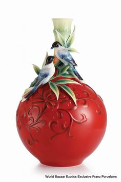 a red vase with two birds sitting on top of it