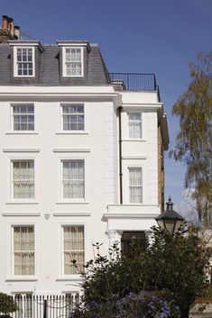 a large white building with lots of windows on the top floor and some bushes in front of it