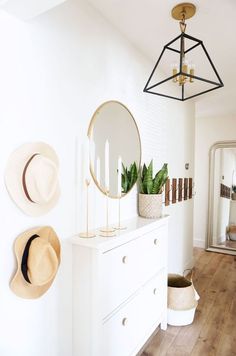 a white dresser topped with a mirror next to a wall mounted candle holder and hat rack