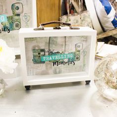 a small white box sitting on top of a table next to flowers and other items