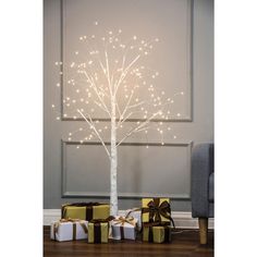 a white tree with lights and presents under it