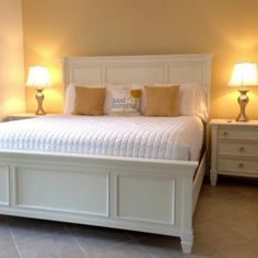 a white bed sitting in a bedroom next to two lamps on either side of it