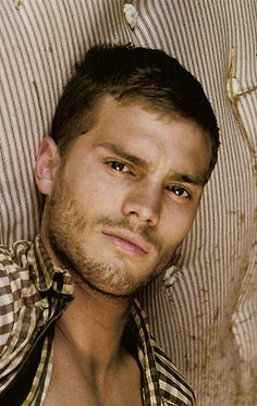 a shirtless man laying on top of a bed next to a striped wallpaper