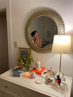 a woman is sitting in the reflection of a mirror on top of a white dresser