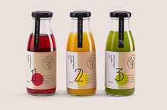 three different types of juice in glass bottles with labels on each side and the same color