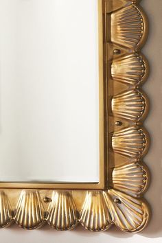 a gold framed mirror with scallop shells on it