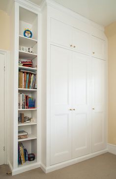 an empty room with white closets and bookshelves in the corner, along with carpeted flooring