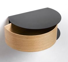 a black and wood shelf on the wall with an oval shaped drawer in it's center