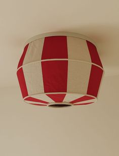 a red and white striped lamp shade hanging from the ceiling in a room with beige walls