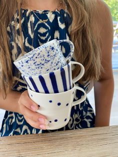 a woman holding a stack of blue and white cups with matching napkins in her hand