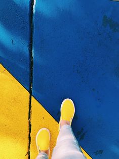 a person with yellow shoes standing in front of a blue and yellow wall