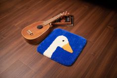 a ukulele and a duck rug on a wooden floor