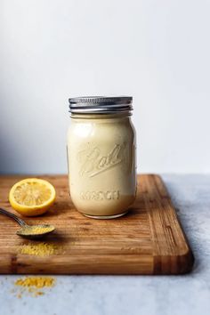 a mason jar with a spoon next to it on a cutting board and lemon wedges