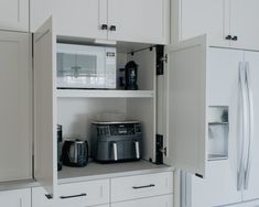 a kitchen with white cupboards and appliances in the cabinets, including a coffee maker