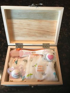 an open wooden box with baby items in it