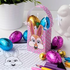 an easter basket filled with chocolate eggs next to colored markers and pencils on a table