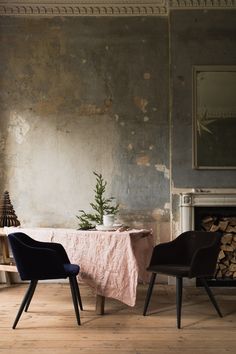 two chairs and a table in front of a fireplace