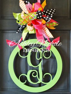 a door hanger with a monogrammed letter and bow hanging on it's side