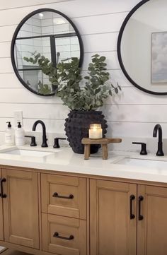 a bathroom with two sinks and mirrors on the wall next to it is a potted plant