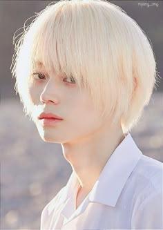 a young man with blonde hair wearing a white shirt and looking off to the side