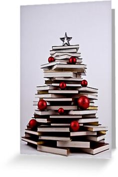 a christmas tree made out of books with red balls on top and silver stars on the top