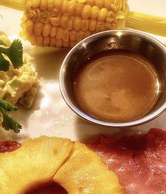 an assortment of food on a plate including corn, bacon, and pineapple slices