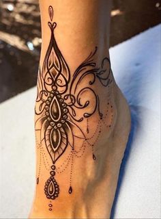 a woman's foot with an intricate tattoo design on the side of her leg