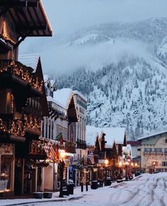 the town is covered in snow and lit up with christmas lights on it's buildings