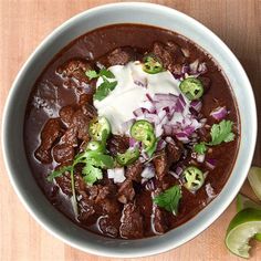 a bowl of chili beef with sour cream and cilantro garnishes