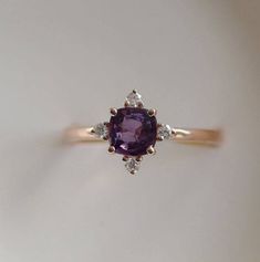 This Engagement ring features a Purple sapphire in cushion cut. The sapphire is natural untreated, eye clean and sparkling. It is set in a 5-stone setting flanked by 4 diamonds. This ring would make a perfect engagement ring, anniversary ring or promise ring. The setting is 14k Rose gold, diamonds Stylish Engagement Rings, 5 Stone Ring, Engagement Ring Gemstone, Purple Sapphire Ring, Peach Sapphire Engagement Ring, Cushion Engagement Ring, Ring Cushion, Beautiful Wedding Rings, Gorgeous Engagement Ring