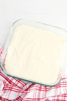 a glass baking dish filled with batter on top of a red and white checkered cloth