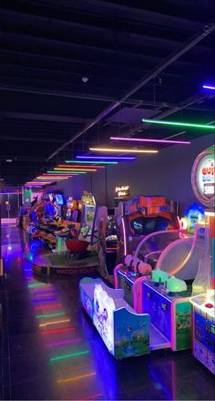 several arcade machines are lined up in a room with neon lights on the ceiling and floor