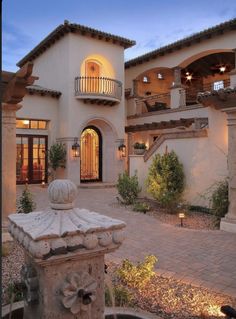 a large house with a fountain in front of it and lights on the side of the building