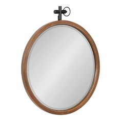 a round mirror hanging on the wall with an iron hook and wooden frame in front of it