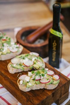 two slices of bread with radishes and cheese on them next to a bottle of wine