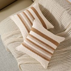 two brown and white pillows sitting on top of a bed next to a pillow case