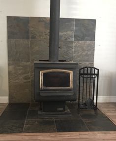 a wood burning stove sitting on top of a wooden floor next to a metal cage