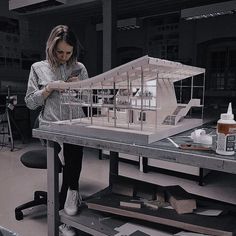 a woman standing in front of a model of a house on top of a table