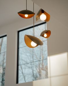 three lights hanging from the ceiling in front of a window