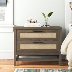 a bedroom with a bed, nightstand and plant on top of the night stand in front of it