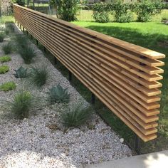 a wooden bench sitting on top of a gravel field next to a lush green park