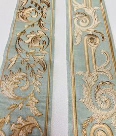 two blue and gold embroidered sashes on a white surface