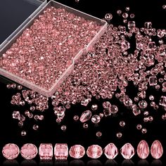 some pink diamonds are laying next to each other on a black surface and one is surrounded by smaller ones